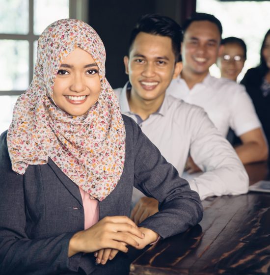 portrait of beautiful asian muslim businesswoman wearing scarf standing in front of her team